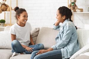 Two people talking about the benefits of alcohol addiction treatment while sitting on a couch